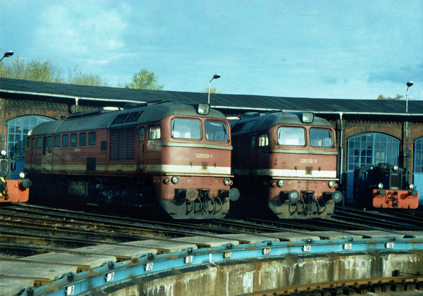 Zwei Lokomotiven der Baurehe DR 120 stehen im Betriebswerk an einer Drehscheibe und warten auf den Einsatz