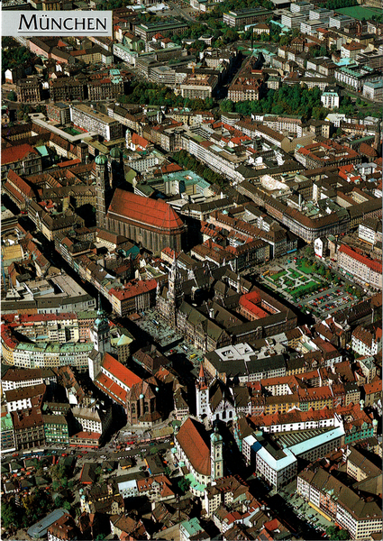 Man sieht die Innenstadt von München von schräg oben. Die wichtigen Wahrzeichen sind zu sehen: Frauenkirche mit ihren zwei Türmen. Das markante Rathaus und der Marienplatz, sowie die Pfarrkiche.