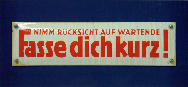ein Foto eines Schildes "Fasse dich kurz! Nimm Rücksicht auf Wartende" in roter Schrift auf weiß-grauem Hintergrund. Man kann Schrauben sehen. Das Bild ist freigestellt und auf einem blauen Hintergrund gedruckt.